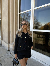 A lady wears an elegant tweed jacket.